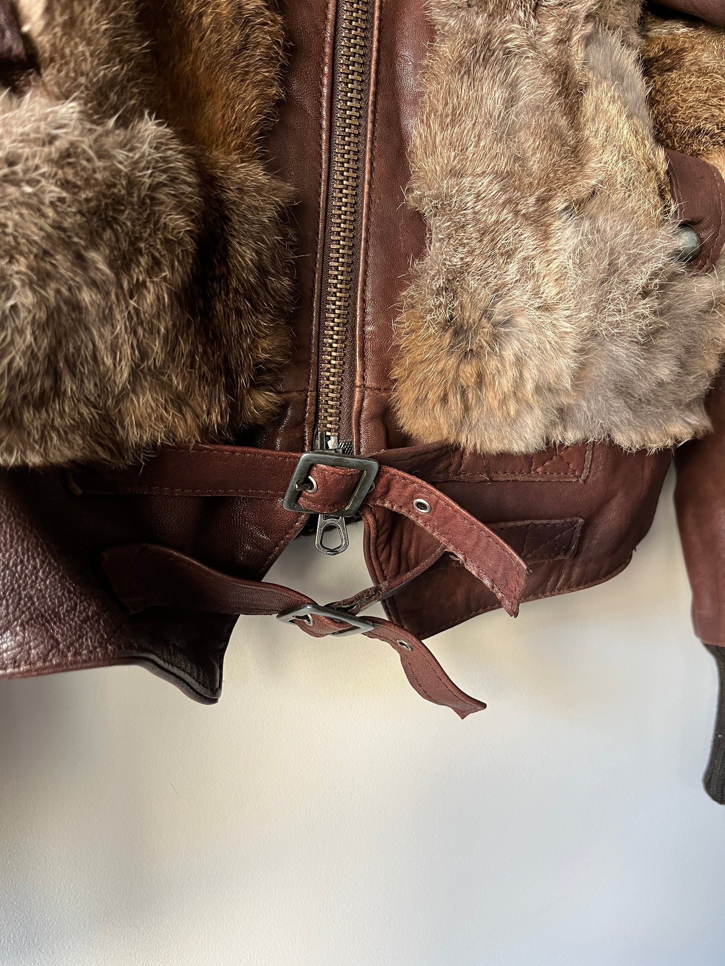 Veste courte en fourrure et cuir à boucles